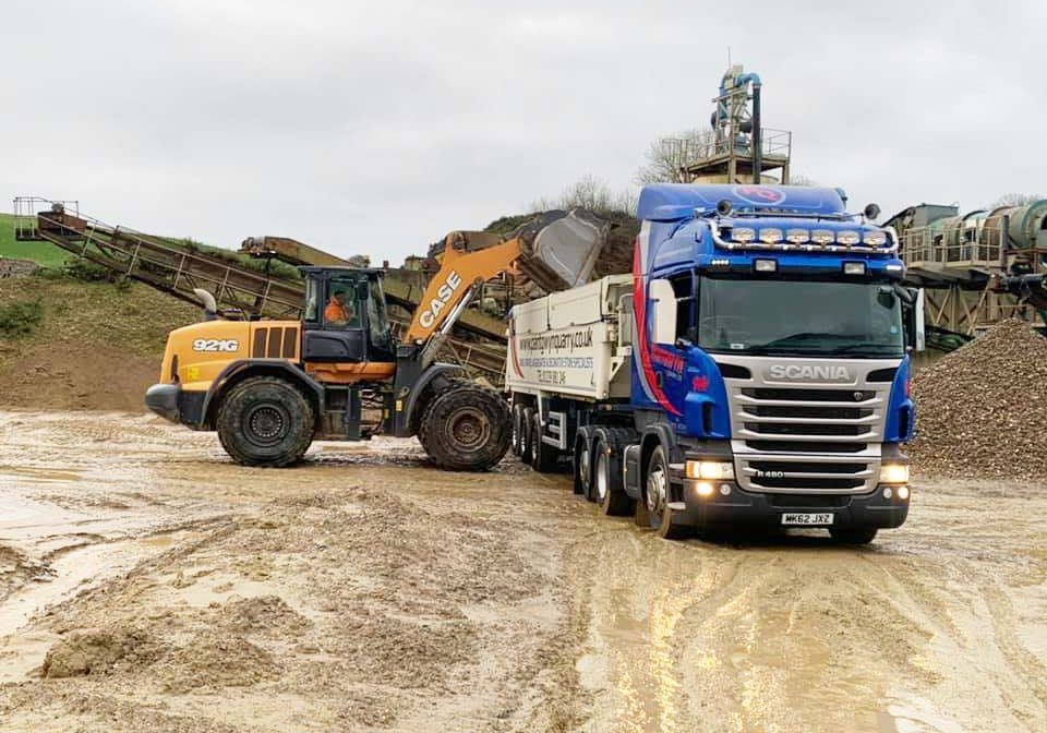 Dunk truck filling large low loader